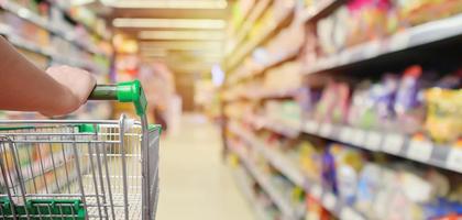 Einkaufswagen im Supermarktgang mit Produktregalen innen defokussiert, unscharfer Hintergrund foto