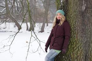 Frau an Baum in Winterlandschaft gelehnt foto