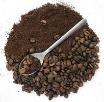 Kaffeebohnen, gemahlener Kaffee und ein Löffel. Das Foto zeigt Kaffeebohnen, gemahlenen Kaffee in Form eines Kreises auf weißem Hintergrund und einen Löffel.