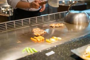 japanischer koch, der fleisch im teppanyaki-restaurant kocht foto