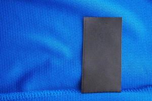 schwarzes leeres Wäschepflegeetikett auf blauem Jersey-Polyester-Sporthemdhintergrund foto