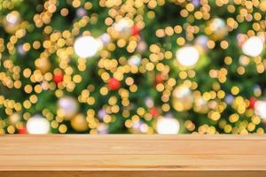 leere hölzerne tischplatte mit abstraktem unschärfeweihnachtsbaum mit dekoration bokeh hellem hintergrund für produktanzeige foto