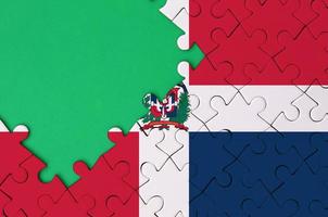 die flagge der dominikanischen republik ist auf einem fertigen puzzle mit freiem grünem kopierraum auf der linken seite abgebildet foto