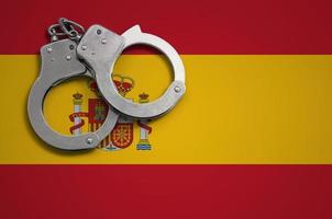spanische flagge und polizeihandschellen. das Konzept der Kriminalität und Straftaten im Land foto