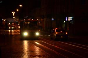 verschwommene Nachtszene des Verkehrs auf der Fahrbahn. defokussiertes Bild von Autos, die mit leuchtenden Scheinwerfern fahren. Bokeh-Kunst foto