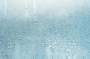 Textur eines Regentropfens auf einem glasnassen, transparenten Hintergrund. in türkis getönt foto