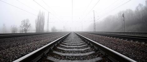 die Bahngleise an einem nebligen Morgen. viele schienen und schwellen gehen in den nebligen horizont. Fisheye-Foto mit erhöhter Verzerrung foto