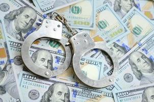 Silberne Polizeihandschellen liegen auf vielen Dollarnoten foto