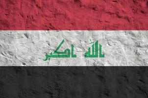 die irak-flagge ist in hellen farben auf einer alten reliefputzwand dargestellt. strukturierte Fahne auf rauem Hintergrund foto