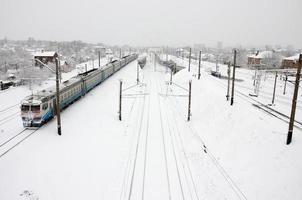 Ein langer Zug von Personenwagen bewegt sich entlang der Bahnstrecke. Eisenbahnlandschaft im Winter nach Schneefall foto
