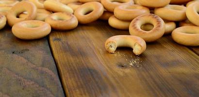 viele frische gelbe bagels liegen auf der oberfläche des alten dunklen holzes. eine beliebte Art von Mehlprodukten. eine der traditionellen russischen Leckereien für Tee foto