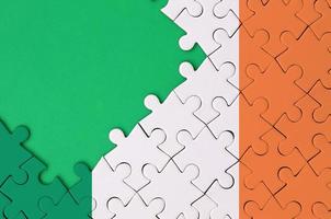Die irische Flagge ist auf einem fertigen Puzzle mit freiem Platz für grüne Kopien auf der linken Seite abgebildet foto