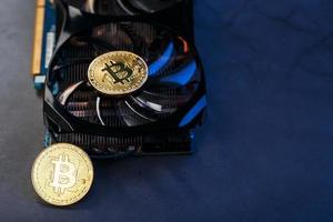 bitcoin-münze auf einer leistungsstarken grafikkarte zum schürfen und verdienen des kryptowährungskonzepts auf dunklem hintergrund. foto