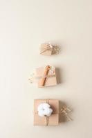 weihnachtliche minimale komposition mit verpackungsgeschenken in handwerkspapier und blumen auf beigem hintergrund. flach liegend, kopierraum foto