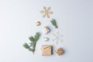 weihnachtsbaumform gemacht mit geschenken im handwerk und weihnachtsdekorationen auf grauem hintergrund. flach liegend, kopierraum foto