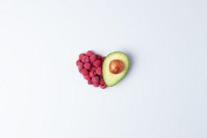 kreatives sommerkonzept. Herzform aus frischen Beeren und Avocado auf grauem Hintergrund. flach liegend, kopierraum. foto