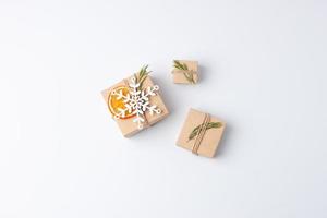 weihnachten minimale komposition mit umweltfreundlichen geschenken in bastelpapier mit rosmarin auf weißem hintergrund. Zero Waste Weihnachtsferienkonzept. flach liegend, kopierraum foto