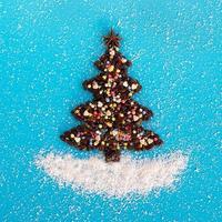 weihnachtsbaum aus kaffeebohnen und dekoriertem anisstern, mehrfarbiger kulinarischer streuung und kokosnusschips auf blauem hintergrund, draufsicht. foto