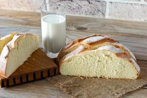 Frisch gebackenes Brot auf einem grauen Küchentisch aus Holz mit einem Glas Milch, hausgemachtem Gebäck. foto