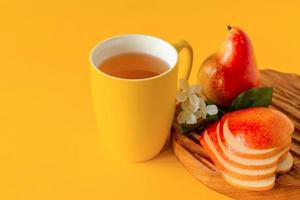 tasse birnensaft und reife birnen auf holzschneidebrett und gelbem hintergrund mit kopienraum. foto