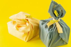 Zero Waste, umweltfreundliche Geschenkverpackung im traditionellen japanischen Furoshiki-Stil, Umweltkonzept, umweltfreundliches Banner. trendfarben des jahres 2021 leuchtendes gelb und ultimatives grau. foto