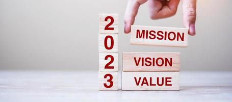 Holzblock mit Text 2023 Mission, Vision und Wert auf Tischhintergrund. auflösung, strategie, lösung, ziel, geschäfts- und neujahrsferienkonzepte foto