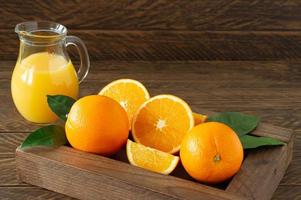 Glas mit frischem Orangensaft mit frischen Früchten auf dunklem Holztisch. foto