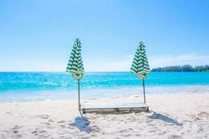 tropischer strandhintergrund als sommerlandschaft mit sonnenschirmliegen und schönem meerblick foto