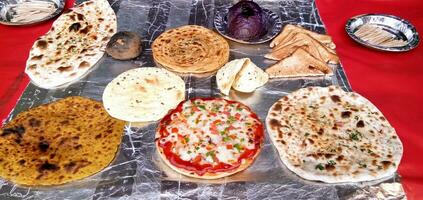 Auswahl an gekochten Chapati, Prantha, Pizza und anderen Speisen foto