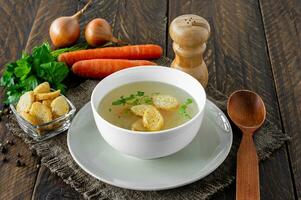 Hühnersuppe mit Gemüse in weißer Schüssel. leckere hausgemachte Brühe auf Holzhintergrund foto