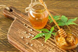 frischer Bio-Honew mit tieferen und Cannabisblättern und -samen auf Holztisch. gesunde ernährung alternative medizin foto