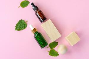 Draufsicht auf frische grüne Minz- oder Minzblätter und Glastropfflaschen mit ätherischem Minzöl auf rosa Hintergrund. natürliches pflanzliches medizinisches aromatisches pflanzenkonzept. foto