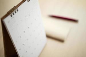 Kalenderseite hautnah auf Holztisch Hintergrund mit Stift und Notizbuch Geschäftsplanung Termin Meeting Konzept foto