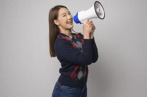 junge lächelnde Frau, die Megaphon über weißem Hintergrundstudio hält. foto