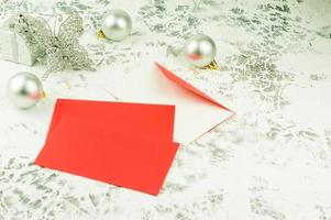 neujahrs- oder weihnachtskomposition aus roten leeren umschlägen für glückwünsche und silberne weihnachtsdekorationen. foto