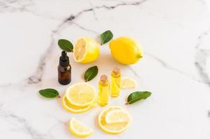 Kosmetisches Zitronenöl und ätherisches Zitrusöl auf einem Marmortisch. Früchte von frischen Zitronen- und Melisenblättern. Naturkosmetik in Glasflaschen. foto