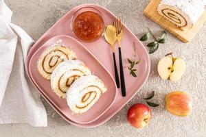 Drei Stück hausgemachter Apfelbrötchen-Biskuitkuchen werden auf einem rosafarbenen Keramikteller und Tablett serviert. Snack-Dessert, Snack. Ansicht von oben. grauer Hintergrund. foto