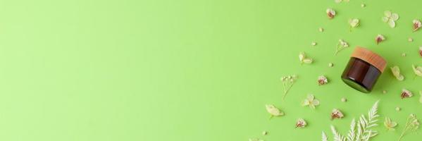 Glas kosmetische Creme mit Blumen auf grünem Hintergrund. flach liegend, kopierraum foto