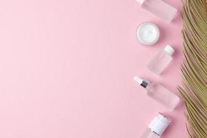 kosmetische hautpflegeprodukte mit palmblatt auf rosa hintergrund. flach liegend, kopierraum foto