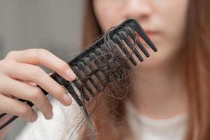 asiatische Frau hat Probleme mit langem Haarausfall an der Kammbürste. foto