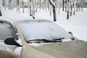 Fragment des Autos unter einer Schneeschicht nach einem starken Schneefall. Die Karosserie des Autos ist mit weißem Schnee bedeckt foto