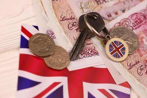 UK-Geldscheine und Schlüssel für Haus aus nächster Nähe. große Menge britischer Pfund und silberner Schlüssel auf dem Tisch. Geschäfts- und Immobilienkonzept foto