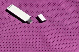 ein moderner tragbarer usb-wi-fi-adapter wird auf der lila sportbekleidung aus polyester-nylonfaser platziert foto