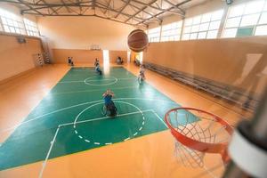 Abschleppfoto eines Kriegsveteranen, der Basketball in einer modernen Sportarena spielt. das Konzept des Sports für Menschen mit Behinderungen foto