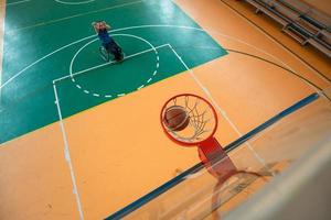 Abschleppfoto eines Kriegsveteranen, der Basketball in einer modernen Sportarena spielt. das Konzept des Sports für Menschen mit Behinderungen foto