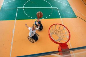 behinderte kriegs- oder arbeitsveteranen gemischte rassen- und alters-basketballteams in rollstühlen, die ein trainingsspiel in einer sportturnhalle spielen. Rehabilitations- und Inklusionskonzept für behinderte Menschen. foto