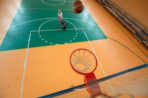 Abschleppfoto eines Kriegsveteranen, der Basketball in einer modernen Sportarena spielt. das Konzept des Sports für Menschen mit Behinderungen foto