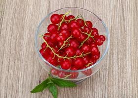 Rote Johannisbeeren in einer Schüssel auf Holzhintergrund foto