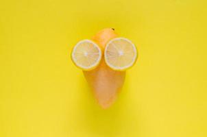 Reife gelbe Mango und Zitronenscheibe als Gesicht mit Augen auf gelbem Hintergrund. Minimales Sommerkonzept. foto