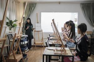 eine asiatische lehrerin unterrichtet und demonstriert den kindern auf acrylfarbbildmalerei auf leinwand im kunstunterricht und lernt kreativ mit geschick in der grundschulstudioausbildung. foto